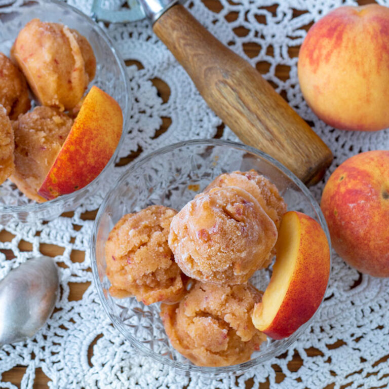 Peach sorbet in small, glass bowls garnished with a peach slice.