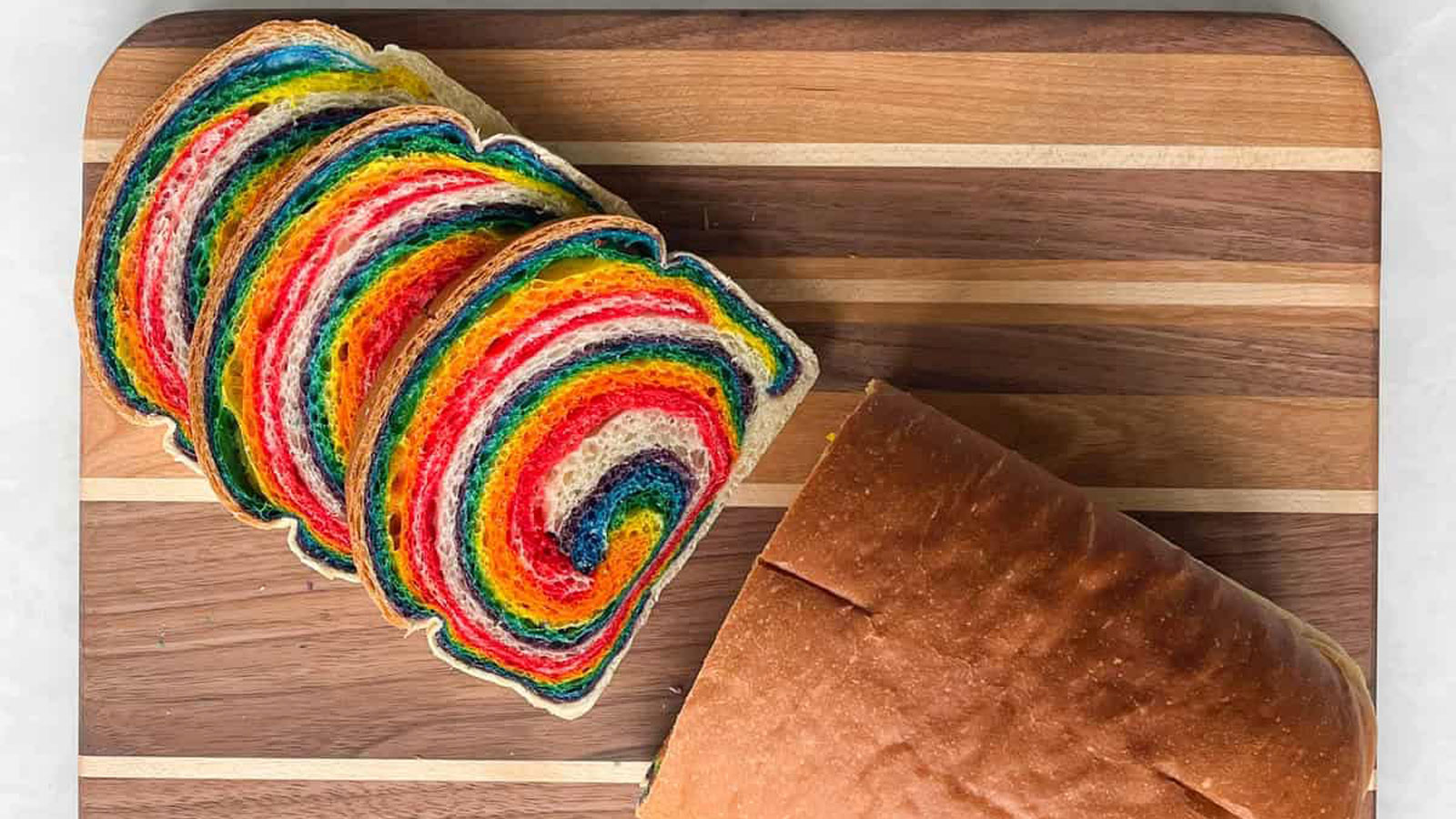 Sliced bread on a board with rainbow-colored dough.