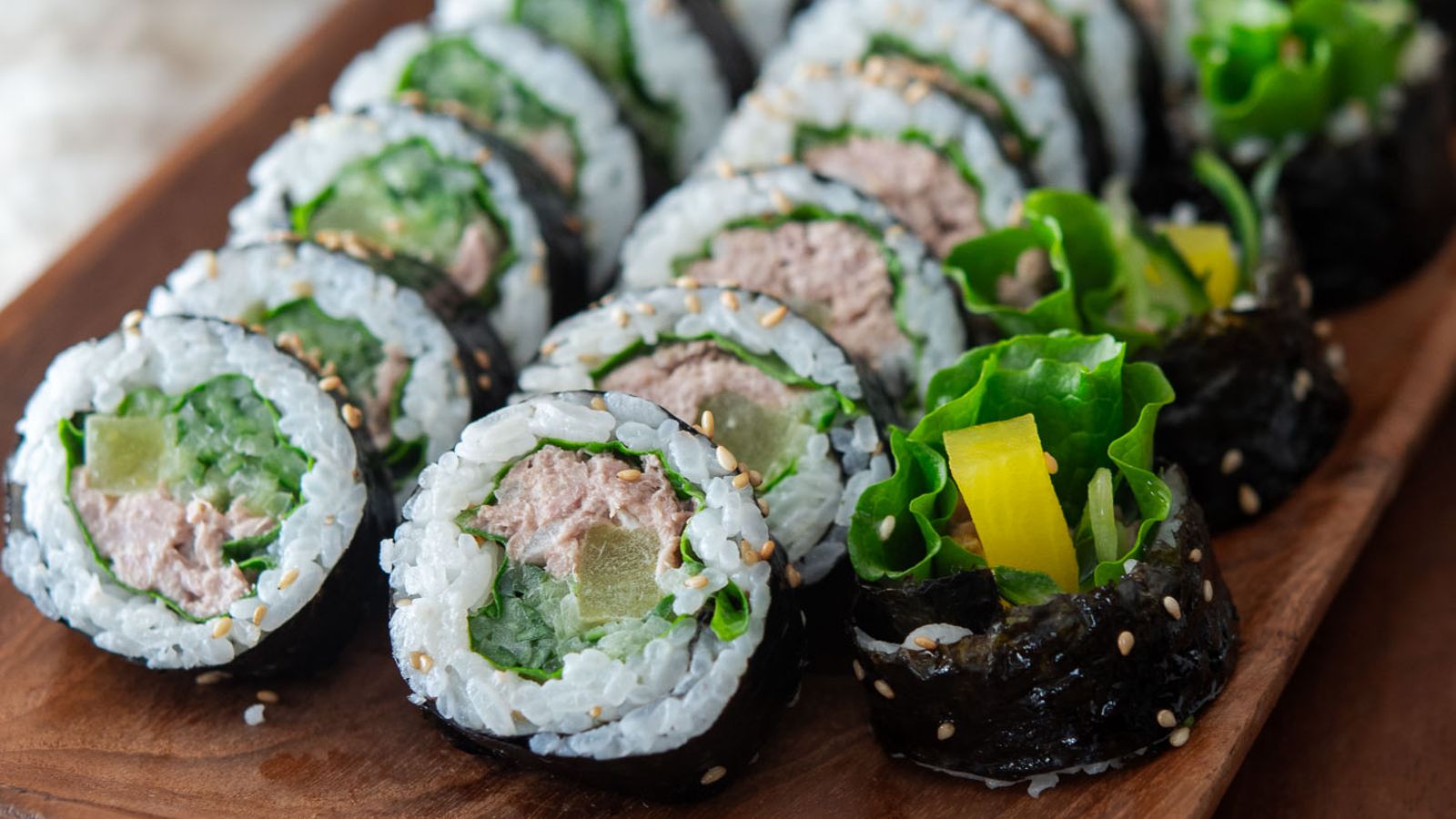 Cucumber kimbap on a wooden plate.