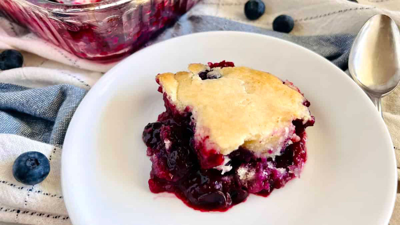 Piece of blueberry cobbler on a white plate.