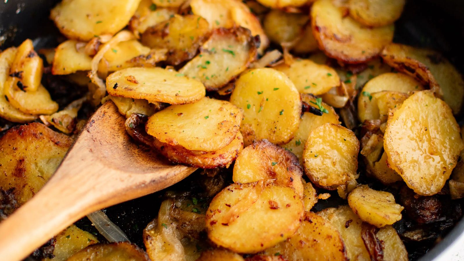 Fried potatoes and onions close up shot.