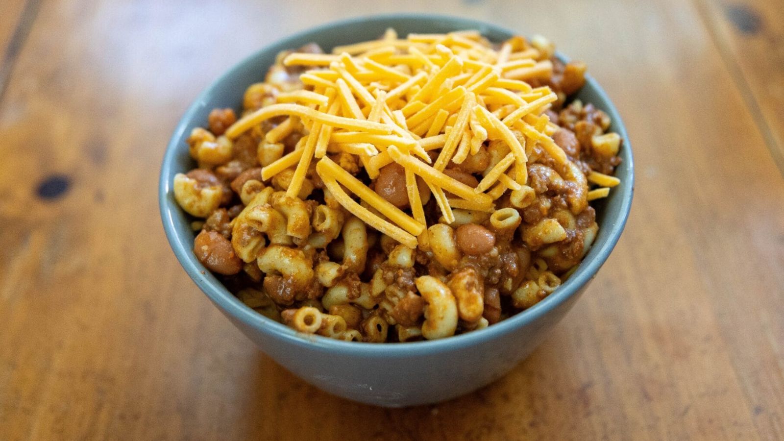 Chili mac in a bowl. with cheese on top.