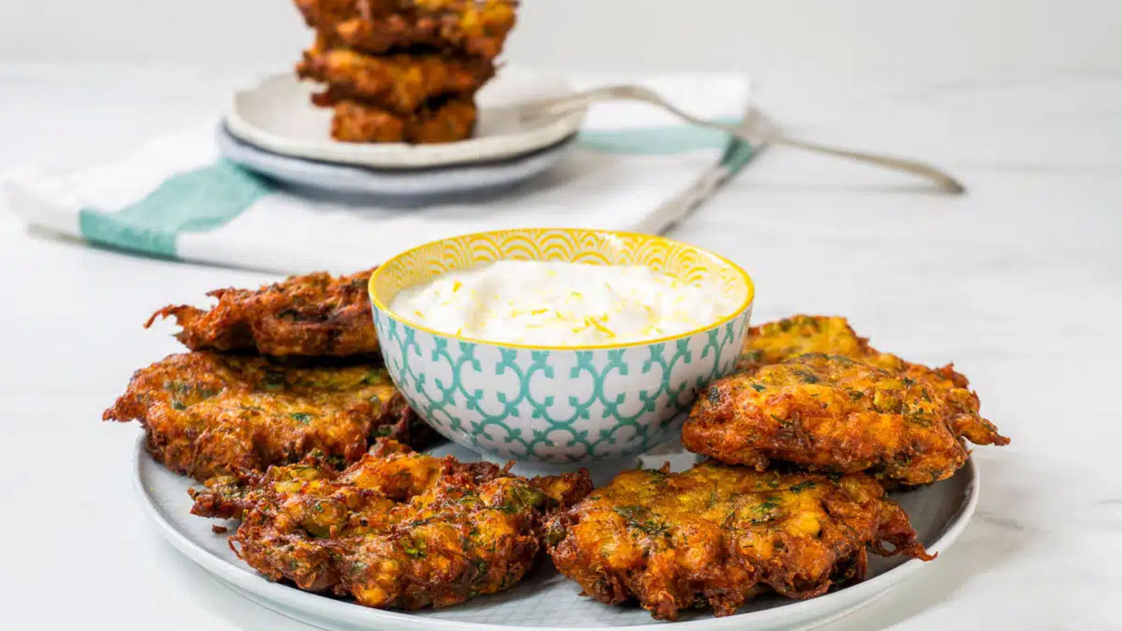 Crispy Mucver on a plate with dipping sauce.
