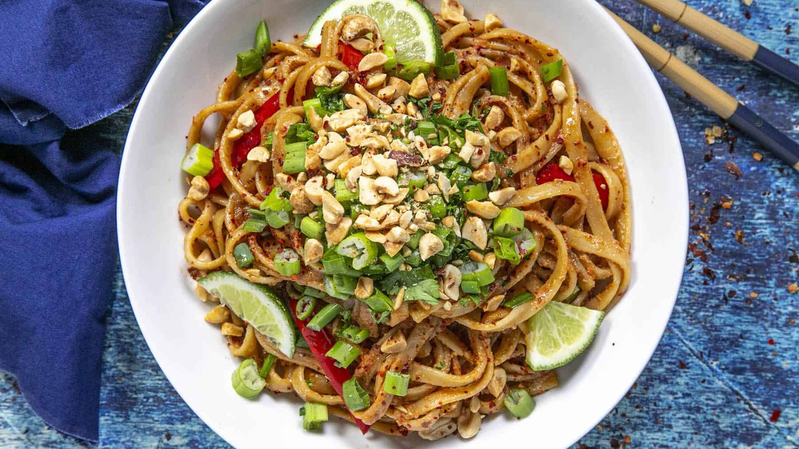 Peanut noodles with sliced lime on sides.
