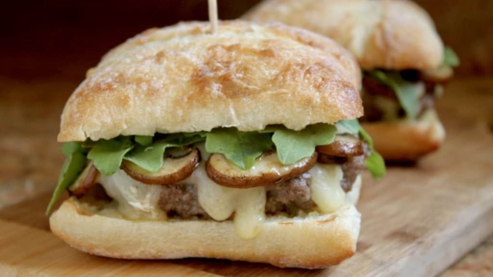 Burger with brie and mushrooms on a board.