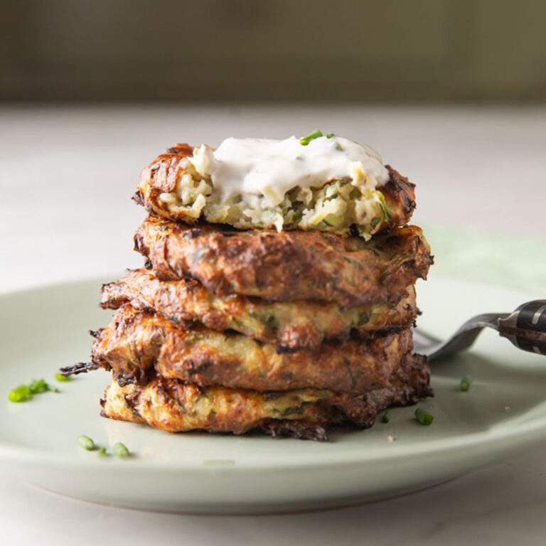 Stack pf zucchini fritters with a bite taken out of the top one.