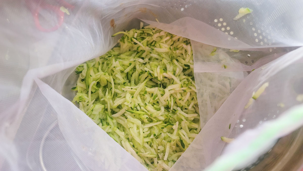 Grated zucchini in cheesecloth bag.