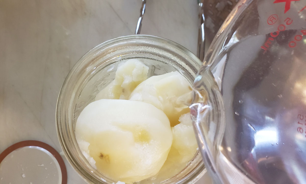 Pouring clean, boiling water into the jar with the potatoes.