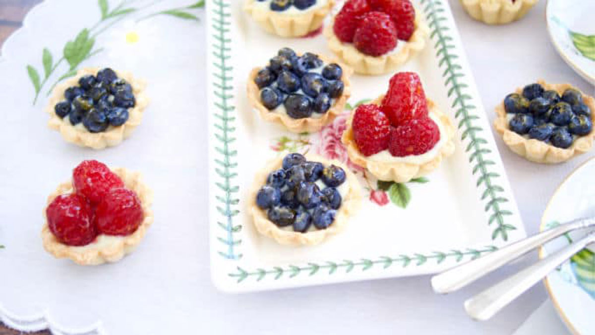 Mini tarts topped with raspberries and blueberries.