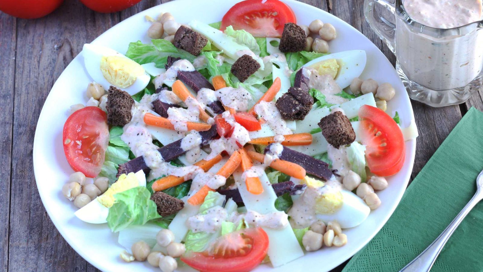 Reuben Dinner Salad with quartered eggs and tomatoes with dark rye croutons and drizzled with thousand Island Dressing and sliced sliced swiss and corned venison, chick peas and julienned carrots
