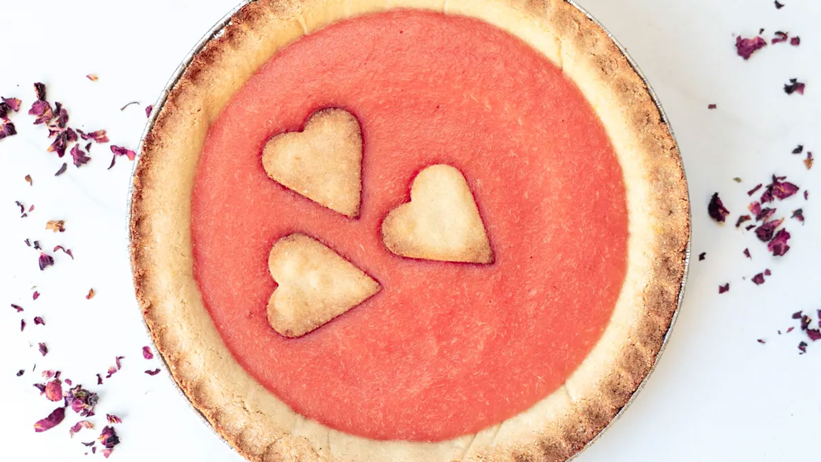 Pink filled pie with 3 hearts cut from pie crust.