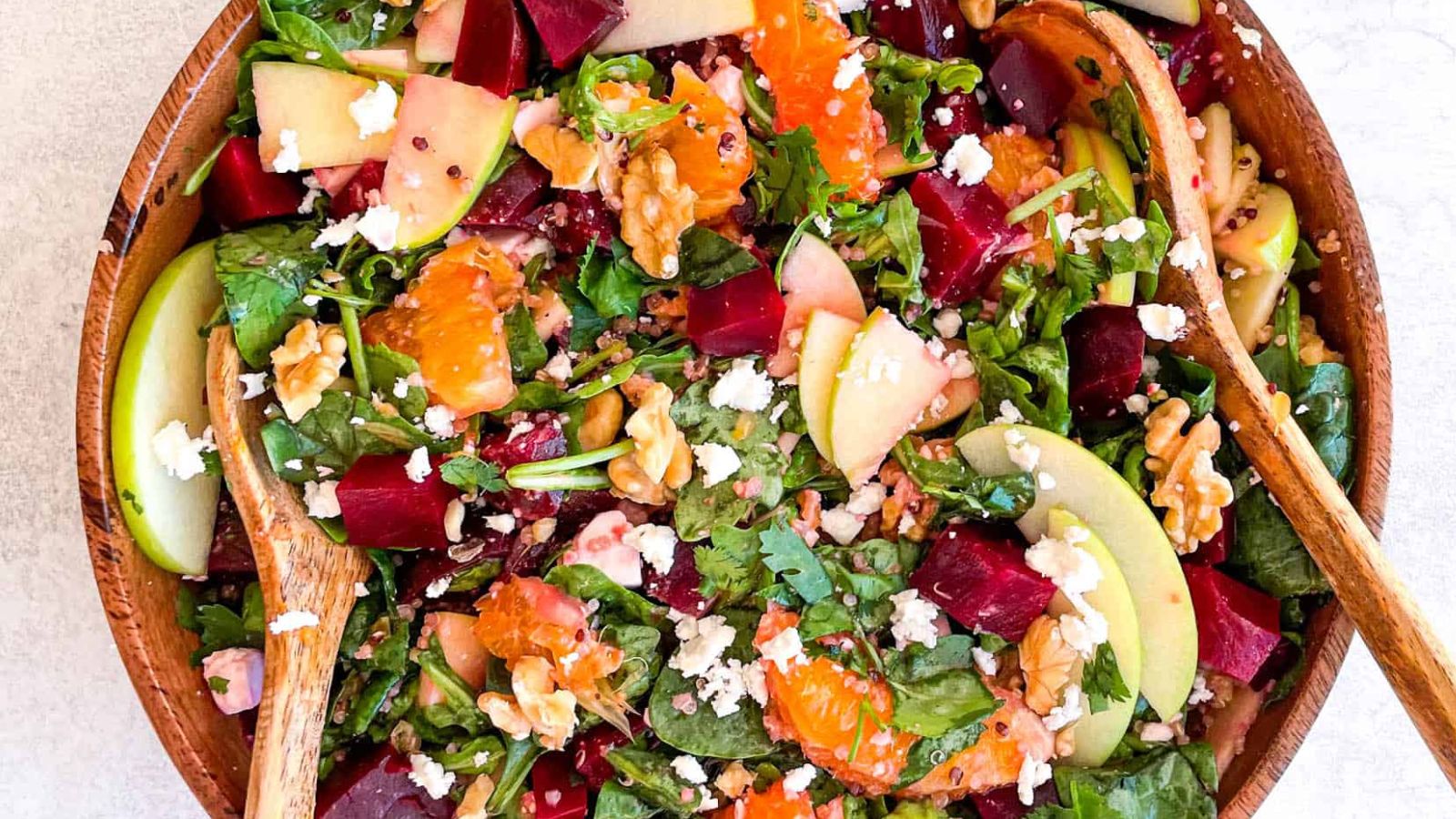 Beetroot salad with feta and orange in a wooden bowl.
