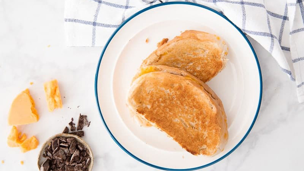 Grilled cheese sandwich on a white plate with a blue ring.