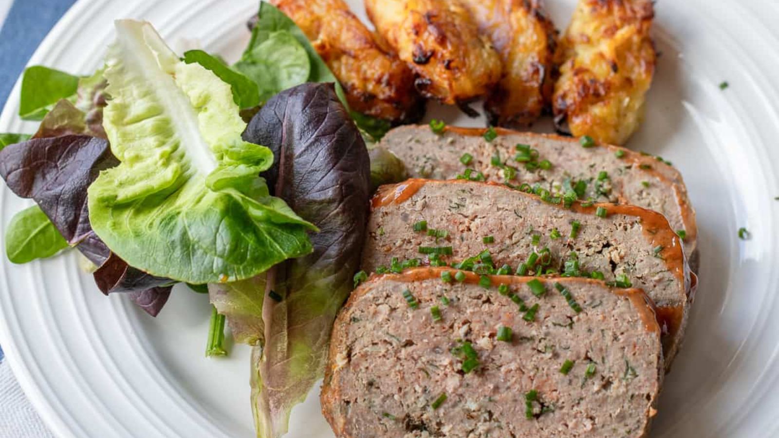 Sliced meatloaf with veggies on the side.