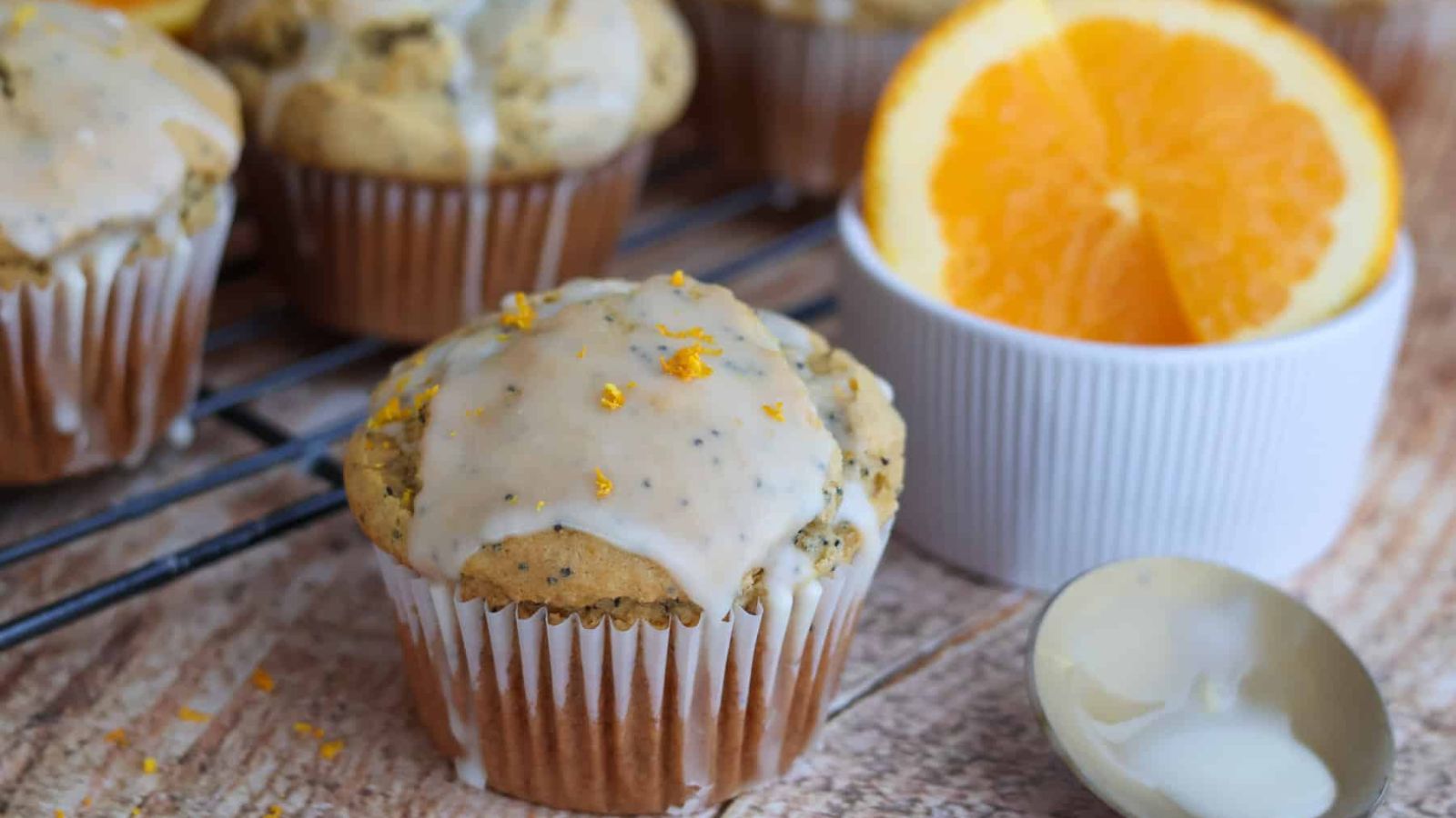 Orange poppy seed muffins with sliced orange on the side.