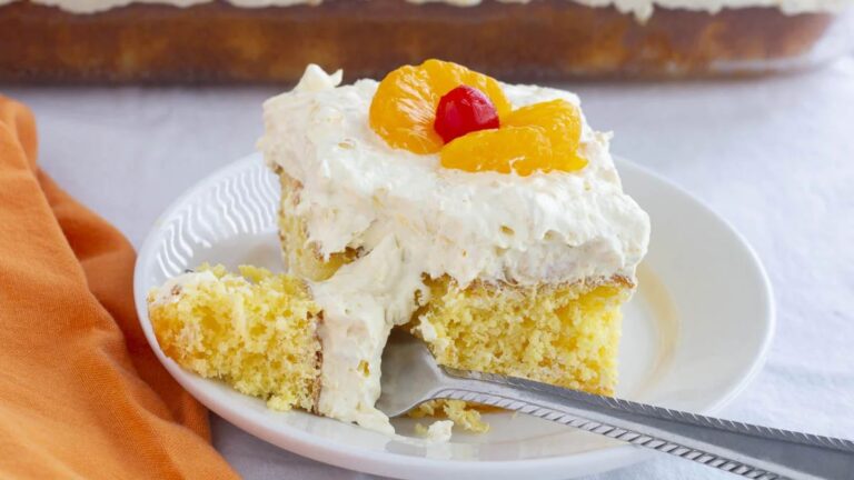 A slice of a cake with oranges and a cherry on top.