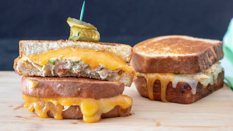 Two tuna melts on a wooden cutting board.