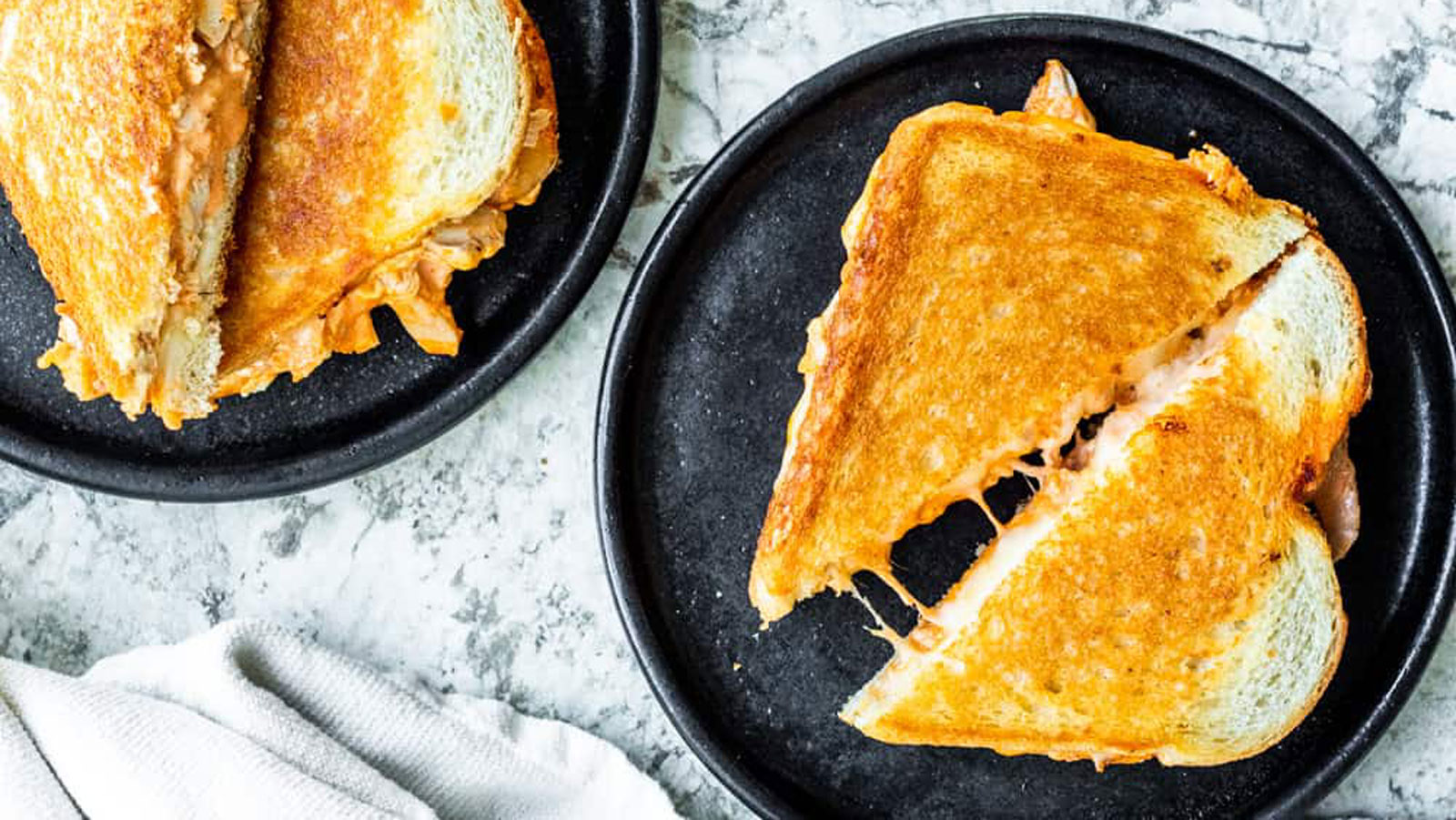 Overhead photo of grilled cheese sandwiches on black plates.