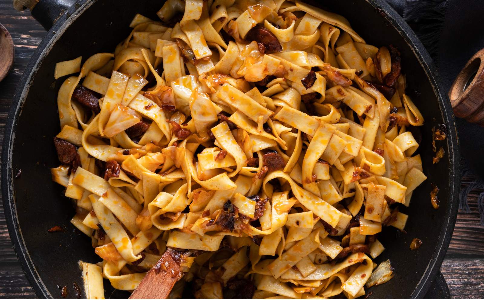 Noodles and beef with cabbage in a black pan.