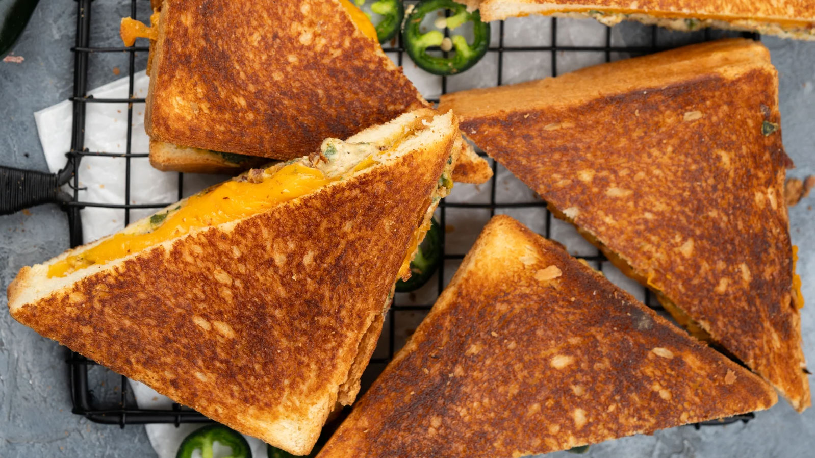 Multiple grilled cheese with slices of jalapenos.