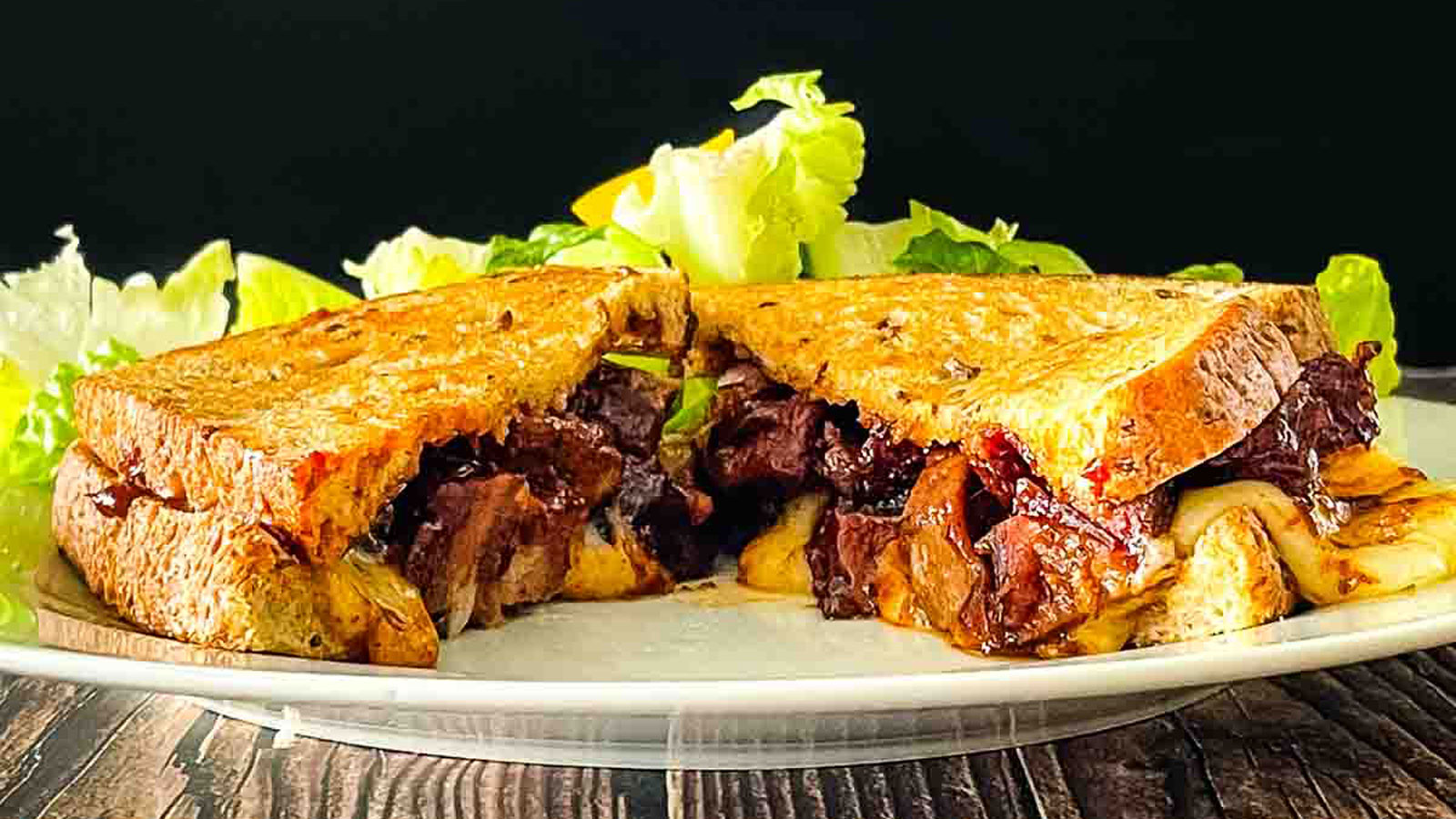 Brisket sandwich with melted cheese on a white plate.