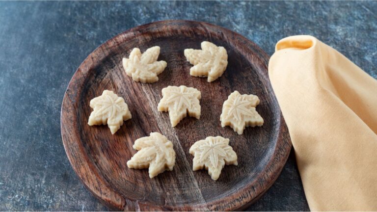 Seven maple candies on a round wooden plate.