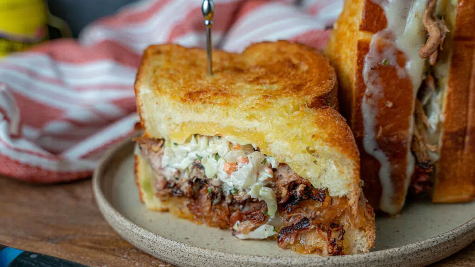 Pulled pork, coleslaw and cheese sandwich on a beige plate.