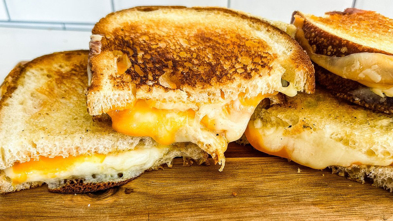 Grilled cheese sandwiches cut in half and stacked on a board.