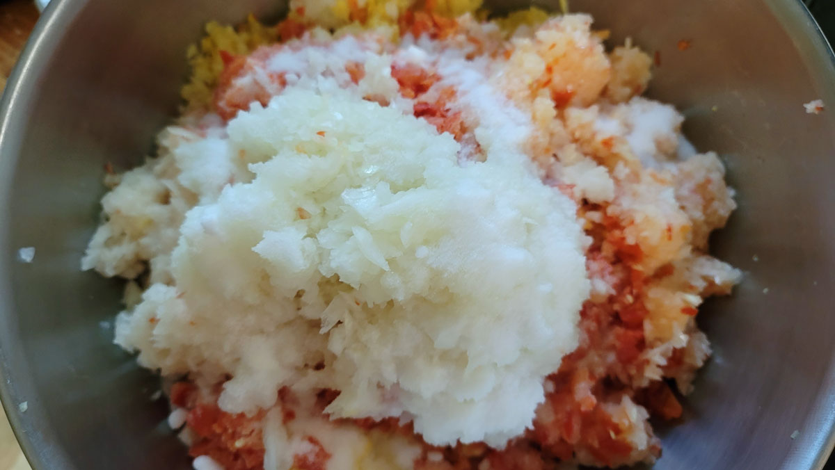Onions, peppers and squash all ground up in a bowl with salt.