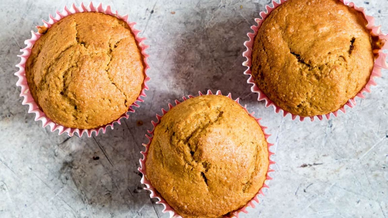 Three muffins on a gray background.