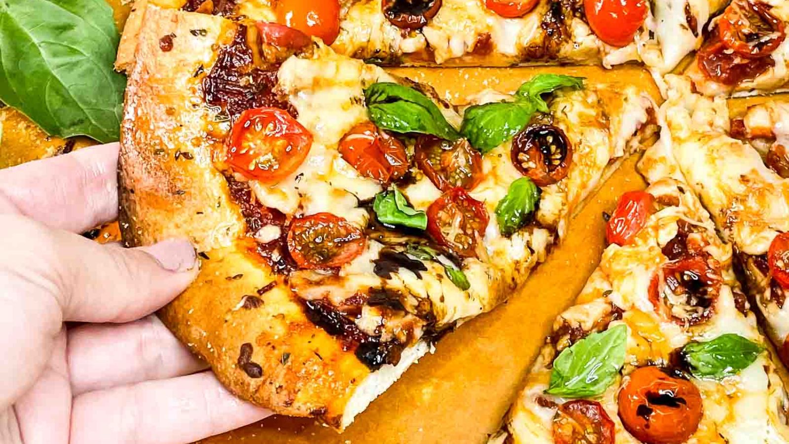 A hand holding a slice of pizza.