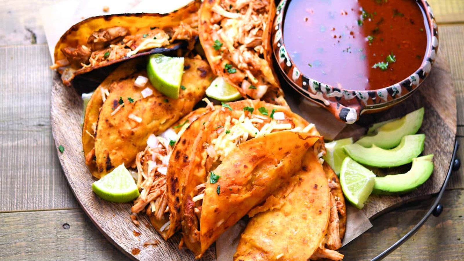 Chicken birria tacos with dip on the side.
