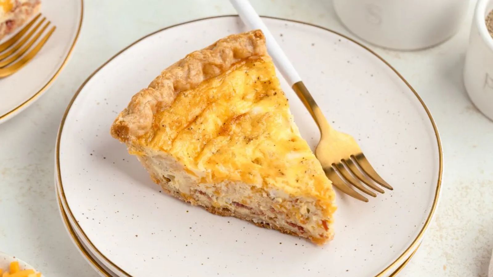 Slice of bacon cheddar quiche on a plate.