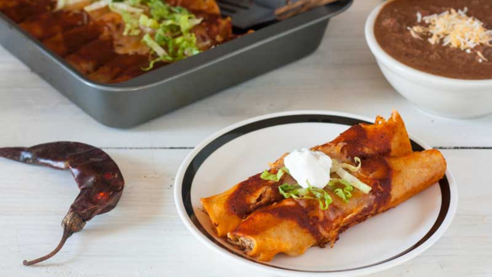 2 chicken enchiladas garnished with lettuce and sour cream