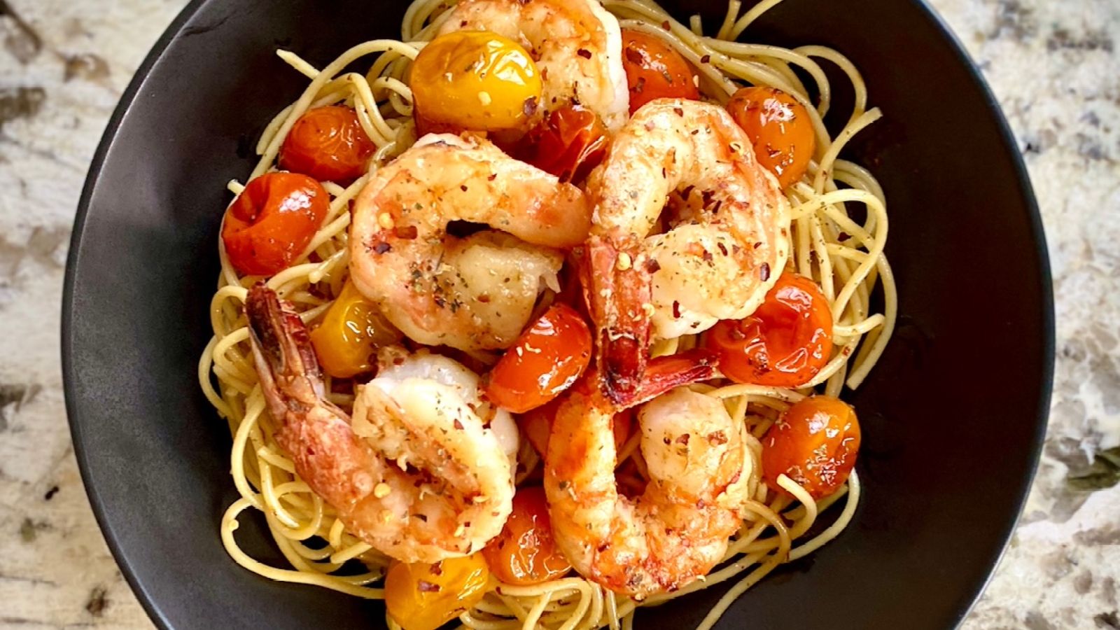 Pasta with garlic shrimp and tomatoes on top.