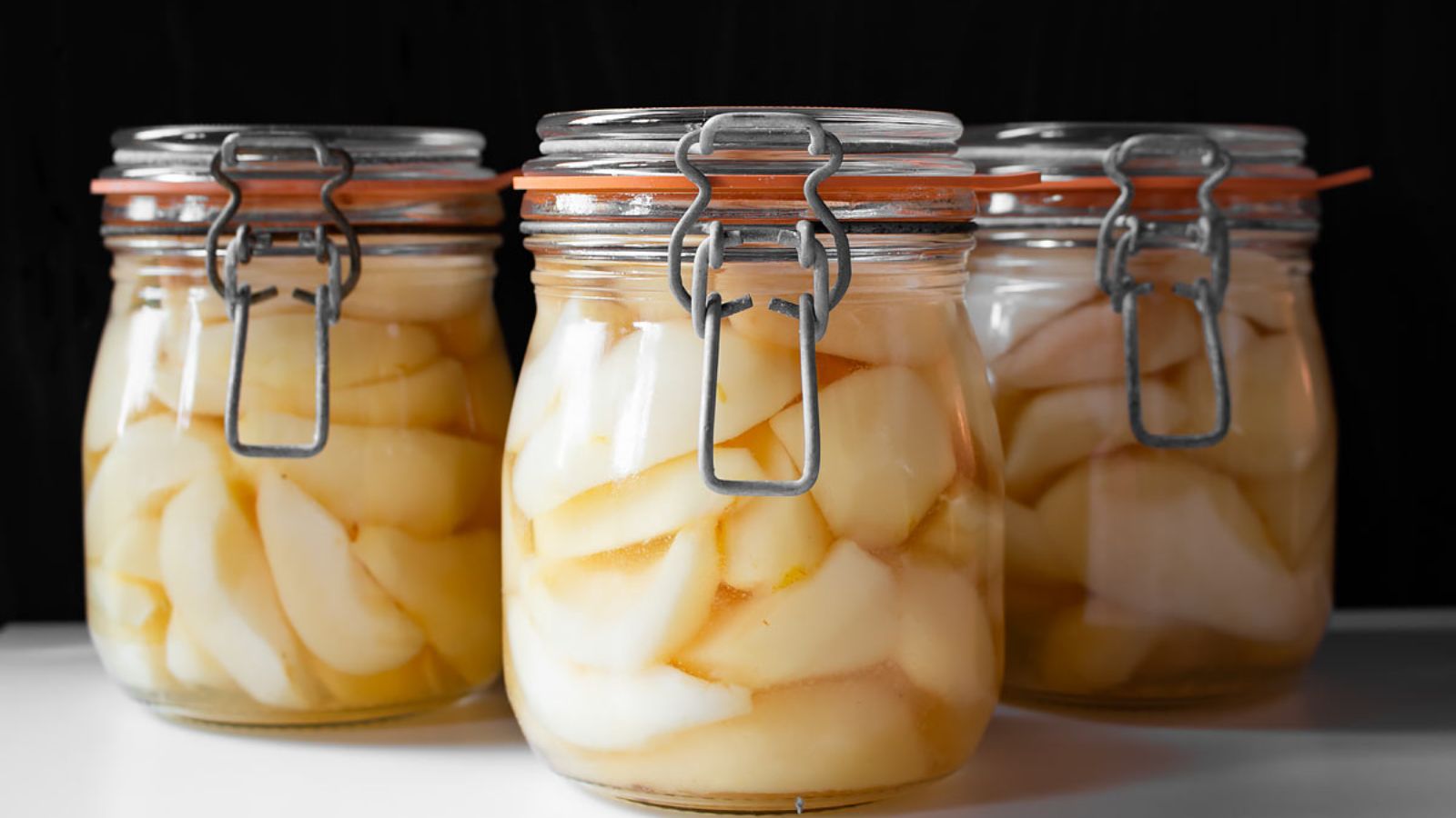 Three jars of pears with syrup.