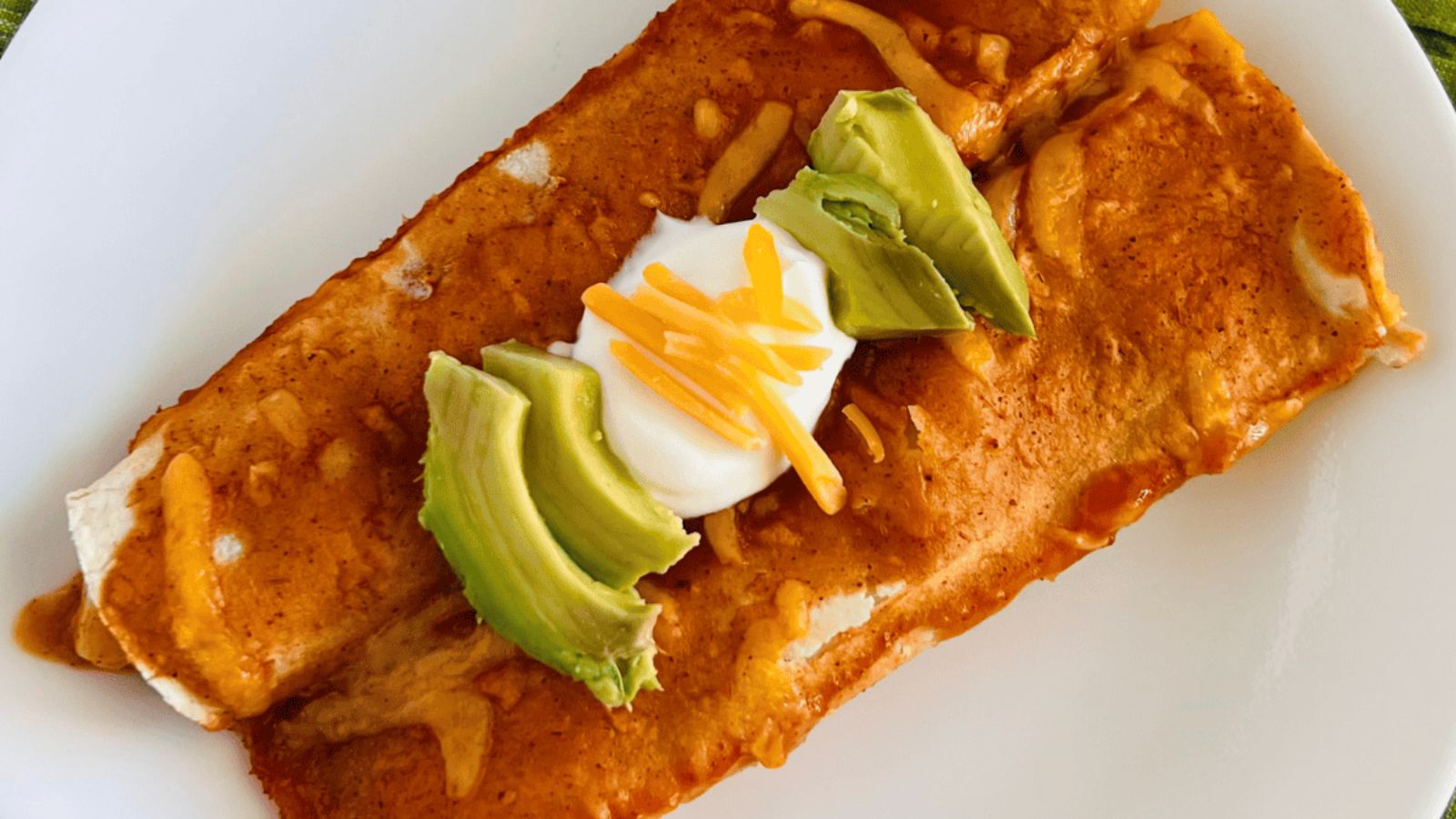 Potato enchiladas with sliced avocados on top.