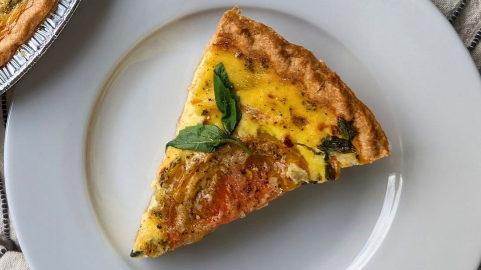 A slice of tomato basil quiche on a plate.