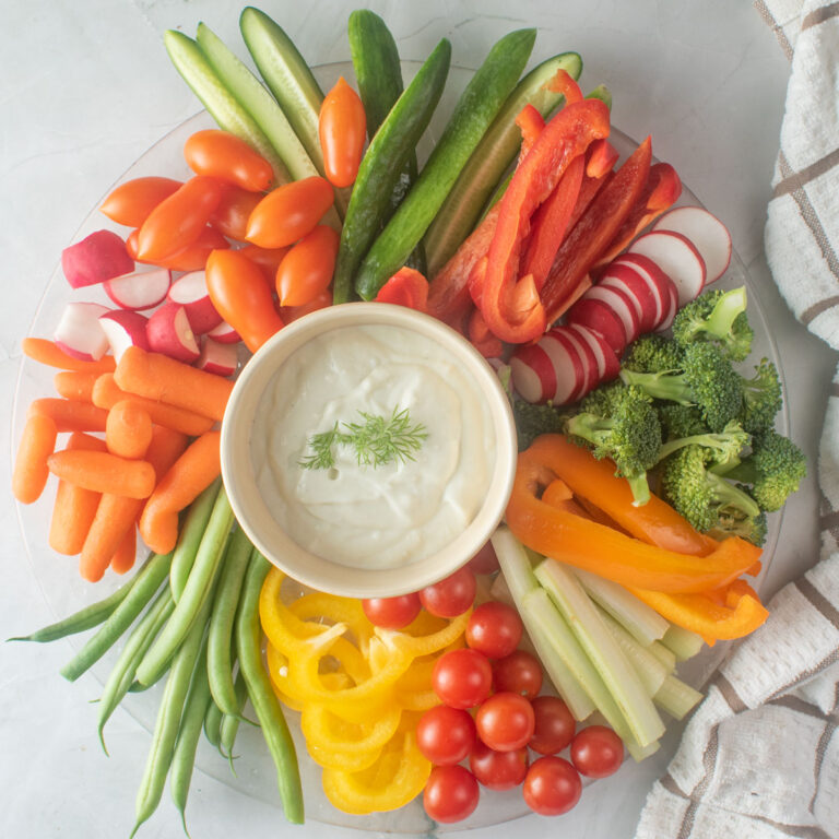 Colorful vegetables on a serving tray with dip in the center.