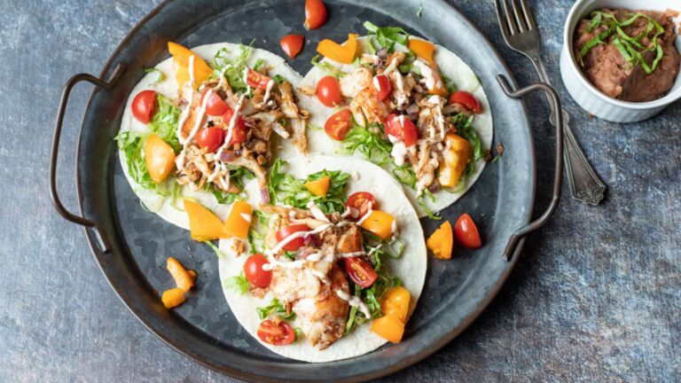 Three lobster tacos on a gray plate.