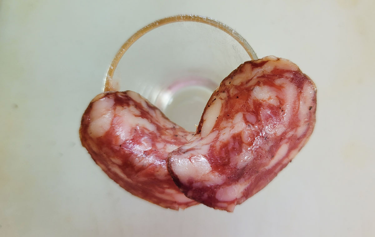 Shot glass with 2 pieces of salami folded over it.