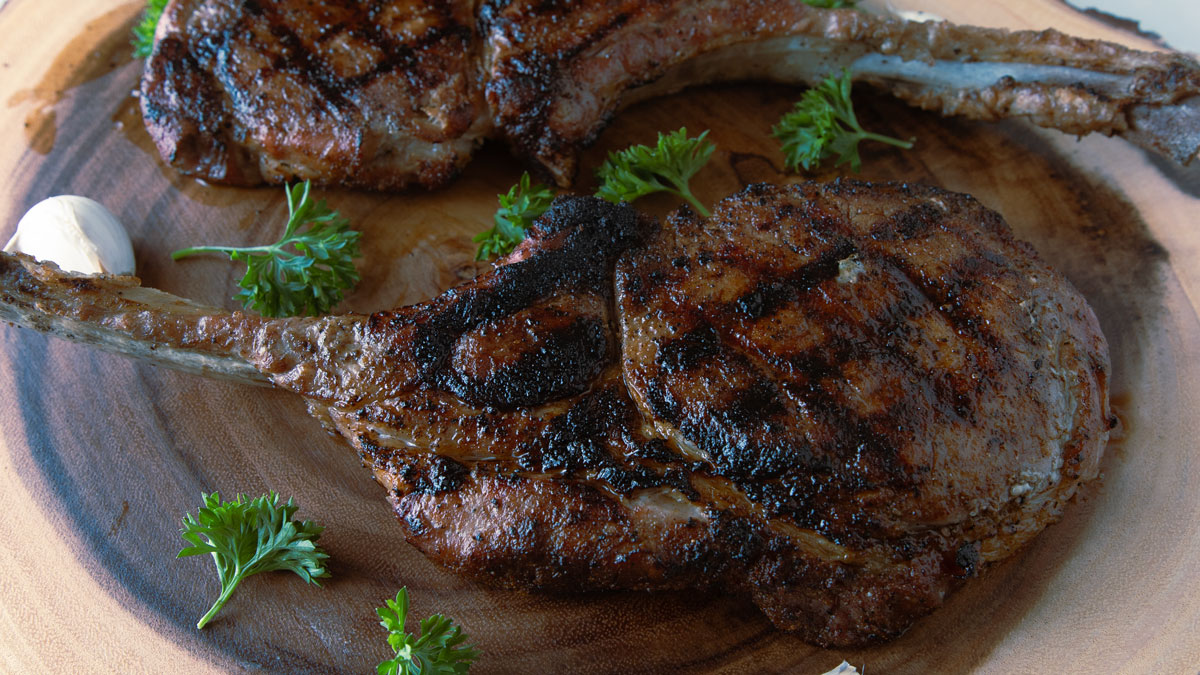 Whole tomahawk pork chop on a wood round.