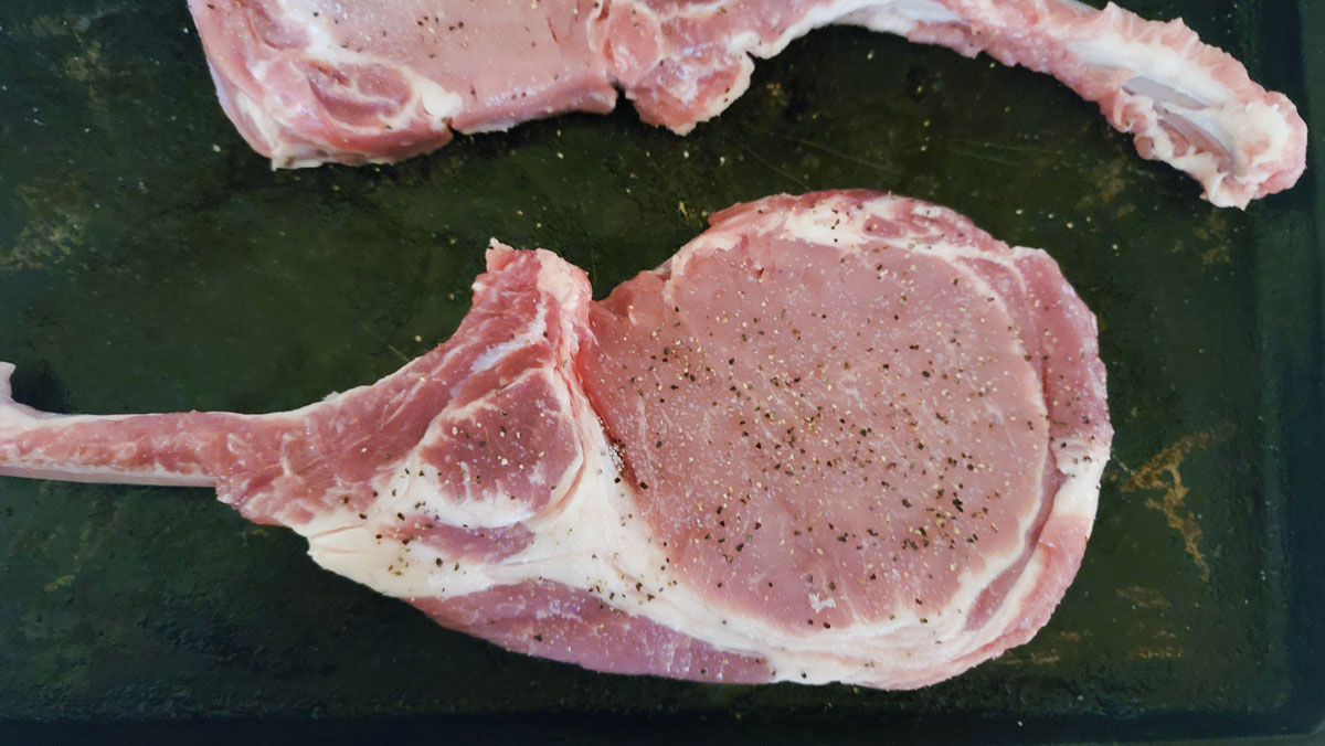 Pork tomahawk chops seasoned with salt and pepper.