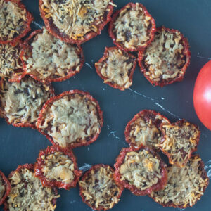 Parmesan tomato chips on a black board.