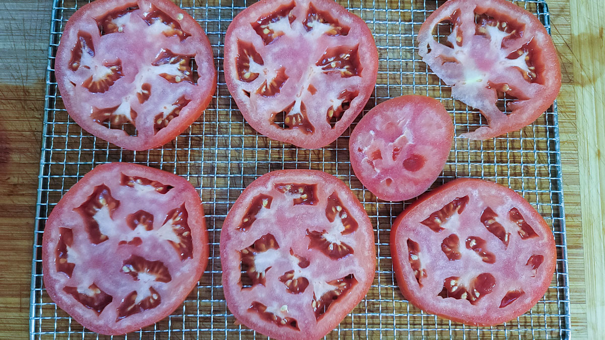 Adding salt and pepper to the tomato slices.