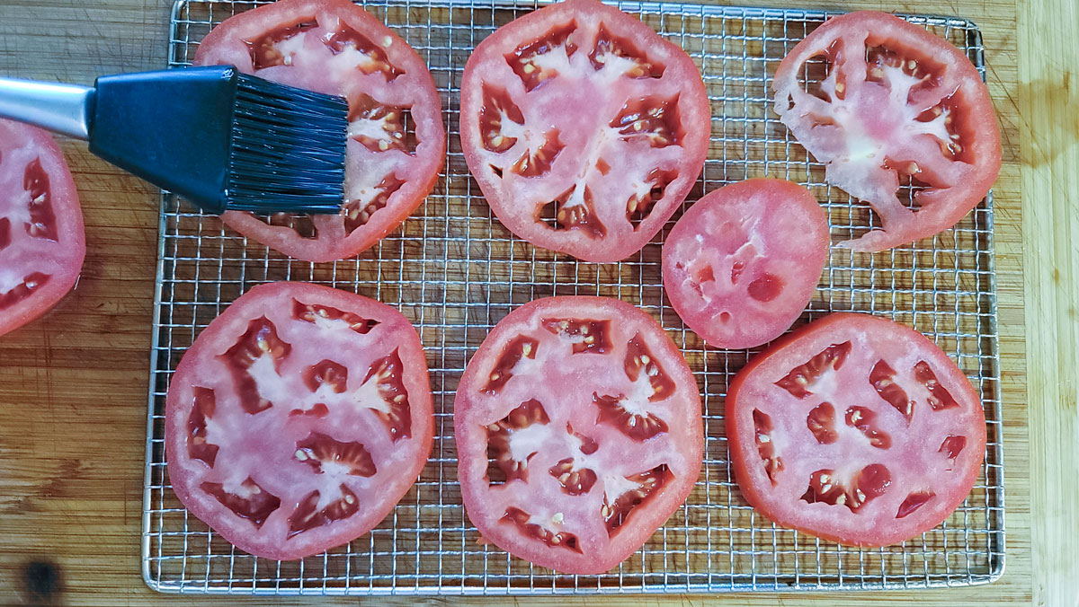 Basting tomato slices with olive oil.
