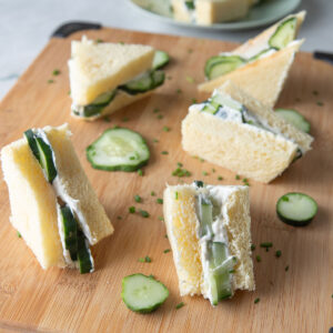 Cucumber sandwiches on a wooden board.