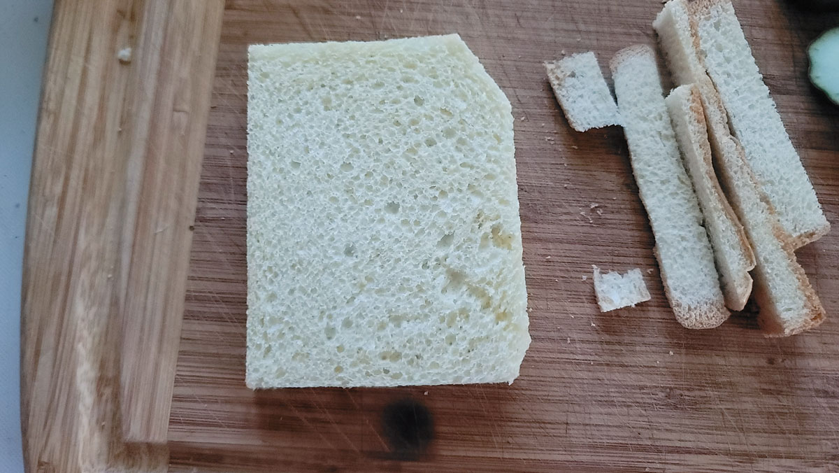 Cut the crusts off of 2 pieces of thin white bread.