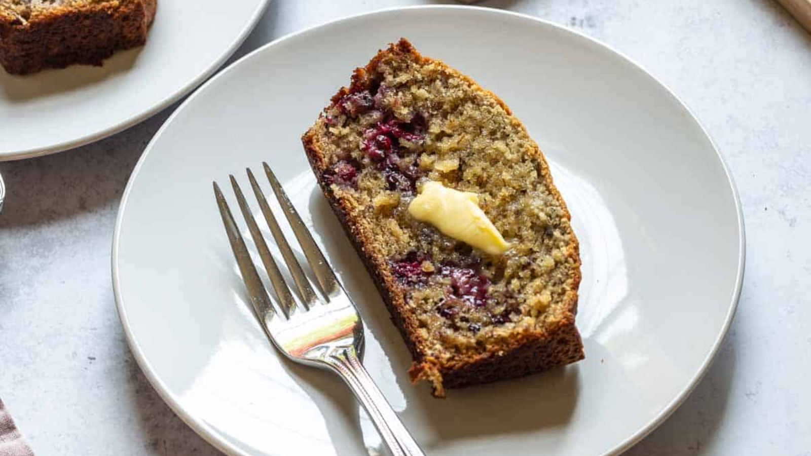 A slice of banana bread with blackberry.