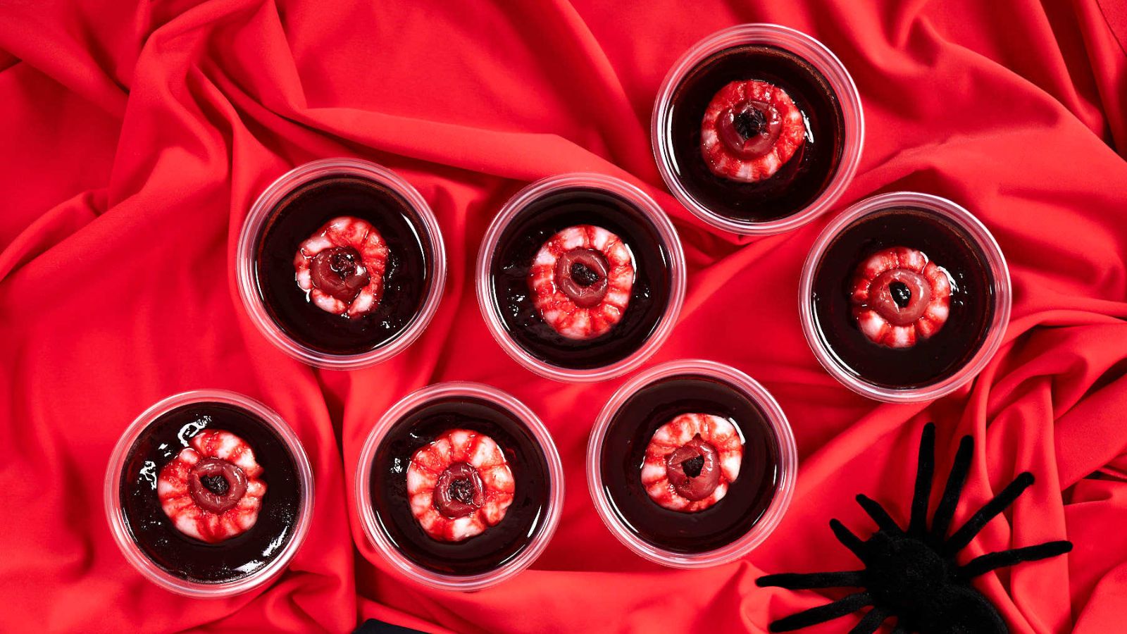 Eyeball jello shots on a red cloth.